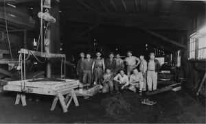 Standing third from left, James (Speedy) Blalock, Nat Cox, Sam Jarrett, far right John Baker standing and Milton Hill kneeling. The furnace and spout can be seen in the distant left behind the portable rack and men.